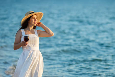woman holding glass of wine by the seaの写真素材