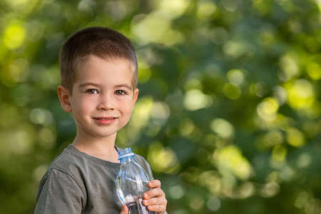 little boy with plastic bottle of water outdoorsの写真素材