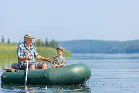 grandfather with grandson together fishing from inflatable boat