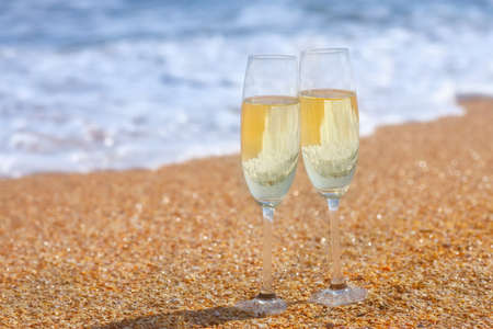 two glasses of champagne on the sea beachの写真素材