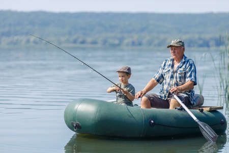 grandfather with grandson together fishing from inflatable boatの写真素材