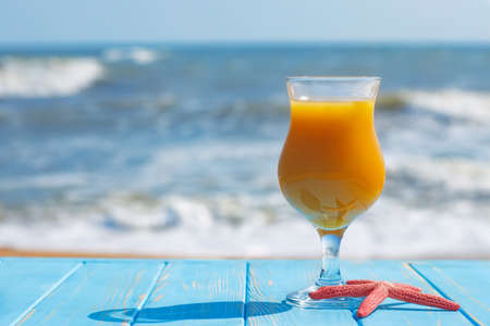 glass of mango juice on table on the sea beachの写真素材