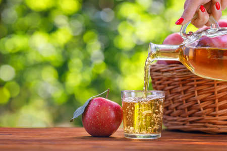apple cider or juice pouring in glass from bottleの写真素材