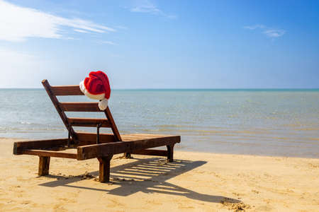 Santa Claus hat on chair lounge on the sea beachの写真素材