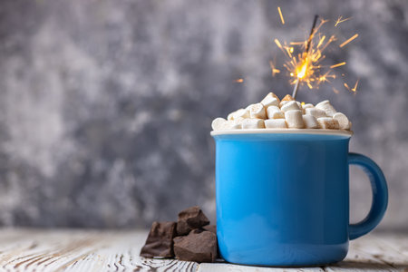 Hot chocolate with marshmallow and burning sparkler on wooden tableの写真素材