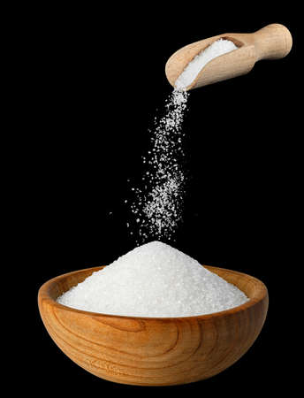 sugar falling from scoop in wooden bowl
