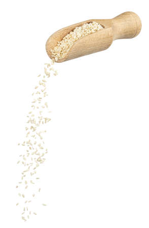 sesame seeds falling from wooden spoon isolatedの写真素材