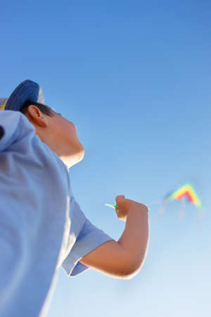 portrait of little boy with flying colorful kiteの写真素材