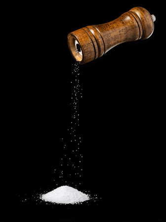 Salt falling from wooden grinder isolated on blackの写真素材