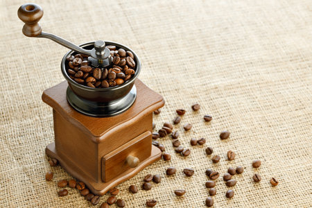 coffee beans in manual grinder on table with burlapの写真素材