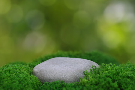 large smooth stone as stand with green moss on natural background. Mockup for cosmetics and other products displayの写真素材