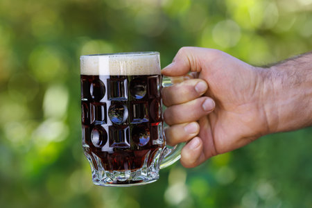 closeup male hand with mug of dark beerの写真素材