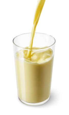 banana or vanilla milk pouring into glass isolated on white backgroundの写真素材