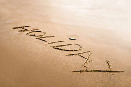 Holiday word written on the sand bright back light effect
