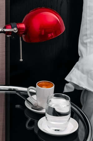 Espresso coffee and water by the bedside morning in hotel roomの写真素材