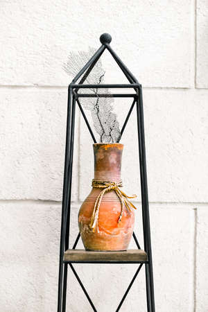 Clay pot coral home house decor elements arrangement on metal stand against the wallの写真素材