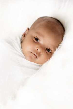 Three weeks old baby sleeping on white blanket cute infant newborn lying down close up shot eyes openの写真素材