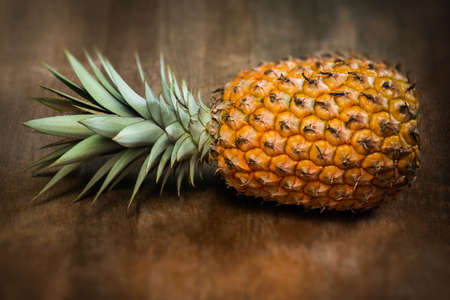 Single one full whole organic pineapple fruit on wooden background ripe fully grown mature, laid down on the sideの写真素材