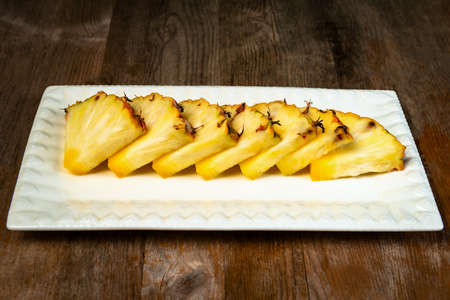 Pineapple fruit cut in wedges on plate wooden background healthy snack