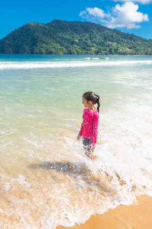 Little girl standing in Maracas Bay Beach Trinidad and Tobago having fun splashing in the waves lookingの写真素材