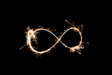 Infinity sign made with sparkler starlight dark black background bright