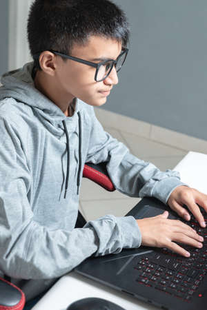 Teen teenager boy home schooling studying room desk pc computer glasses sitting watching homeworkの写真素材