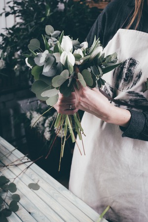 Florist at work on arragment flower bouquet on a wooden tableの写真素材