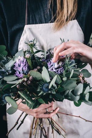 Florist at work on arragment flower bouquet on a wooden tableの写真素材