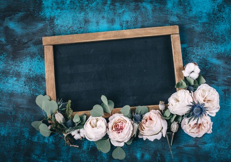 Beautiful flowers frame with pink roses on blue background, flat lay style