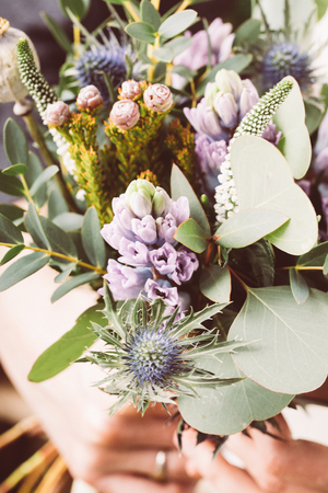 Florist at work on arragment flower bouquet on a wooden tableの写真素材