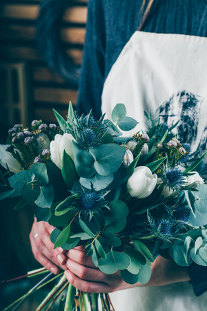 Florist at work on arragment flower bouquet on a wooden tableの写真素材
