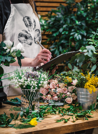 Florist accepts order for delivery flowers and writes to tabletの写真素材