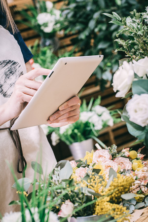 Young girl takes pictures of floral bouquets on a tabletの写真素材