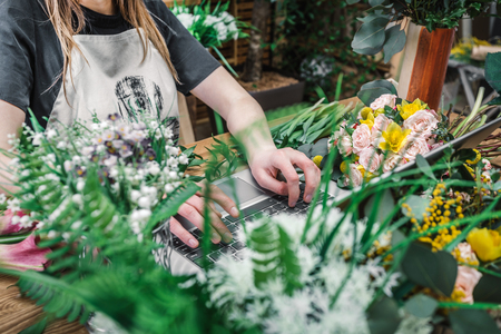 Florist working in modern flower shop on laptopの写真素材