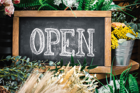 Open sign on wooden table among flowers bouquetの写真素材