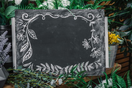 Blank charcoal board among flowers bouquet on florist shopの写真素材