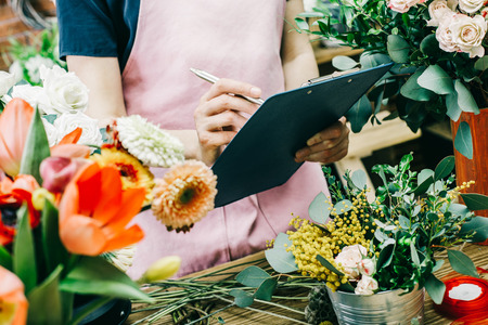 Florist counts and records flowers in florist shop