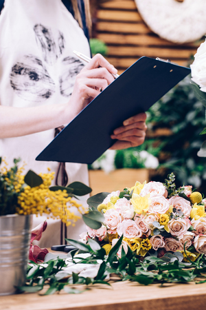 Florist counts and records flowers in florist shopの写真素材