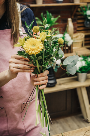 Anonymous woman composing various fresh blooming flowers in beautiful bouquet.の写真素材