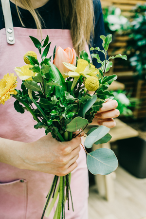 Close-up of florist composing bunch of flowers with green stems.の写真素材