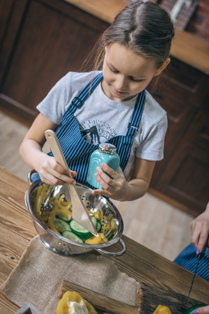 Little girl cooking and seasoning saladの写真素材