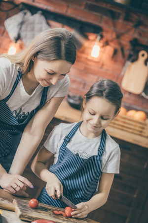 Girl and mother cutting tomatoesの写真素材