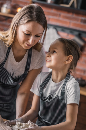 Little girl looking at mother while cookingの写真素材