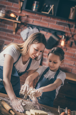Woman preparing knead with daughterの写真素材