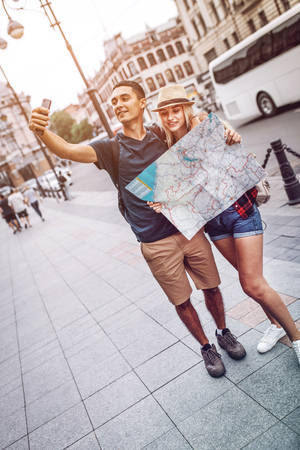 Couple taking selfie with map on streetの写真素材