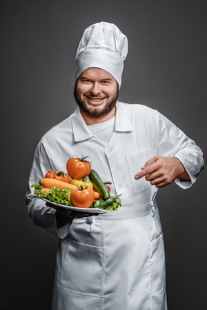 Cheerful chef pointing at fresh vegetablesの写真素材