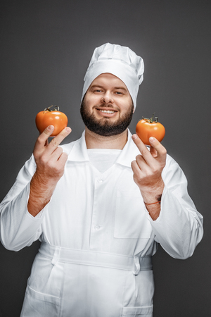Cheerful chef showing fresh tomatoesの写真素材