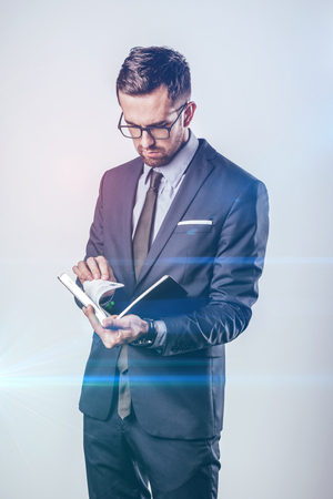 Serious businessman turning pages of notepadの写真素材