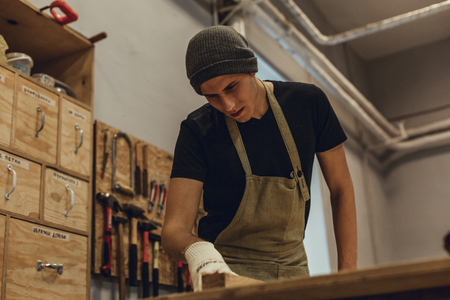 Young carpenter working with wood near tableの写真素材