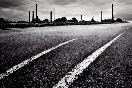 Old asphalt road cracks, splits, fracture and dividing line abstract background. Rough textured traffic transportation highway with damaged, ruined and destroyed surfaceの素材